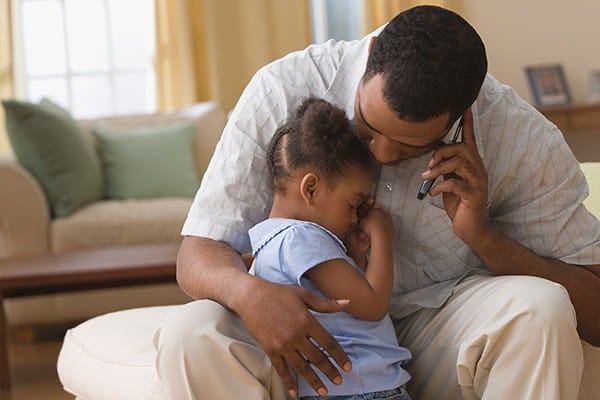 man comforting daughter who needs medical attention