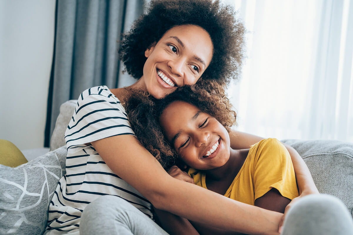 Mom and daughter hugging on couch.