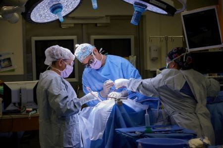 Three healthcare providers operating on a patient