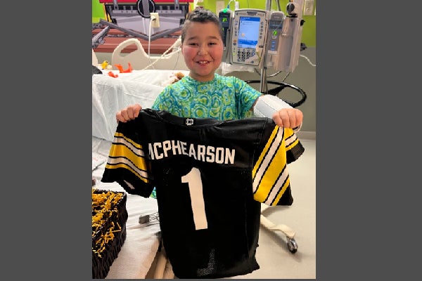 Kayson holding University of Iowa football jersey