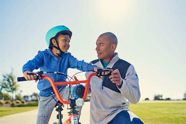 A father teaches his son how to ride a bicycle.