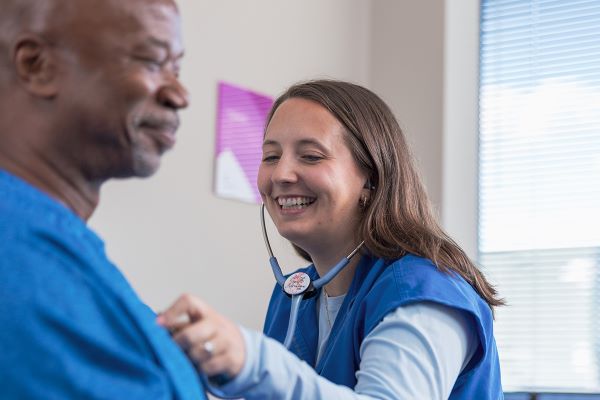 care provider examining patients heart with a stethoscope