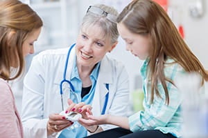 Pediatrician showing a young girl's mother the girl's glucose level.