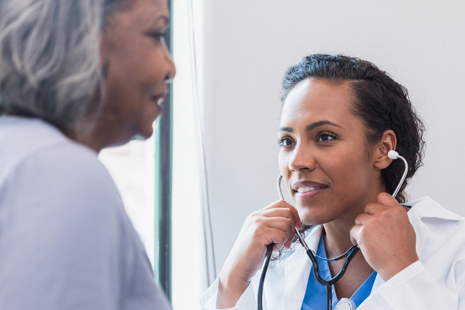 Black female doctor with stethoscope talking to older black patient afib care